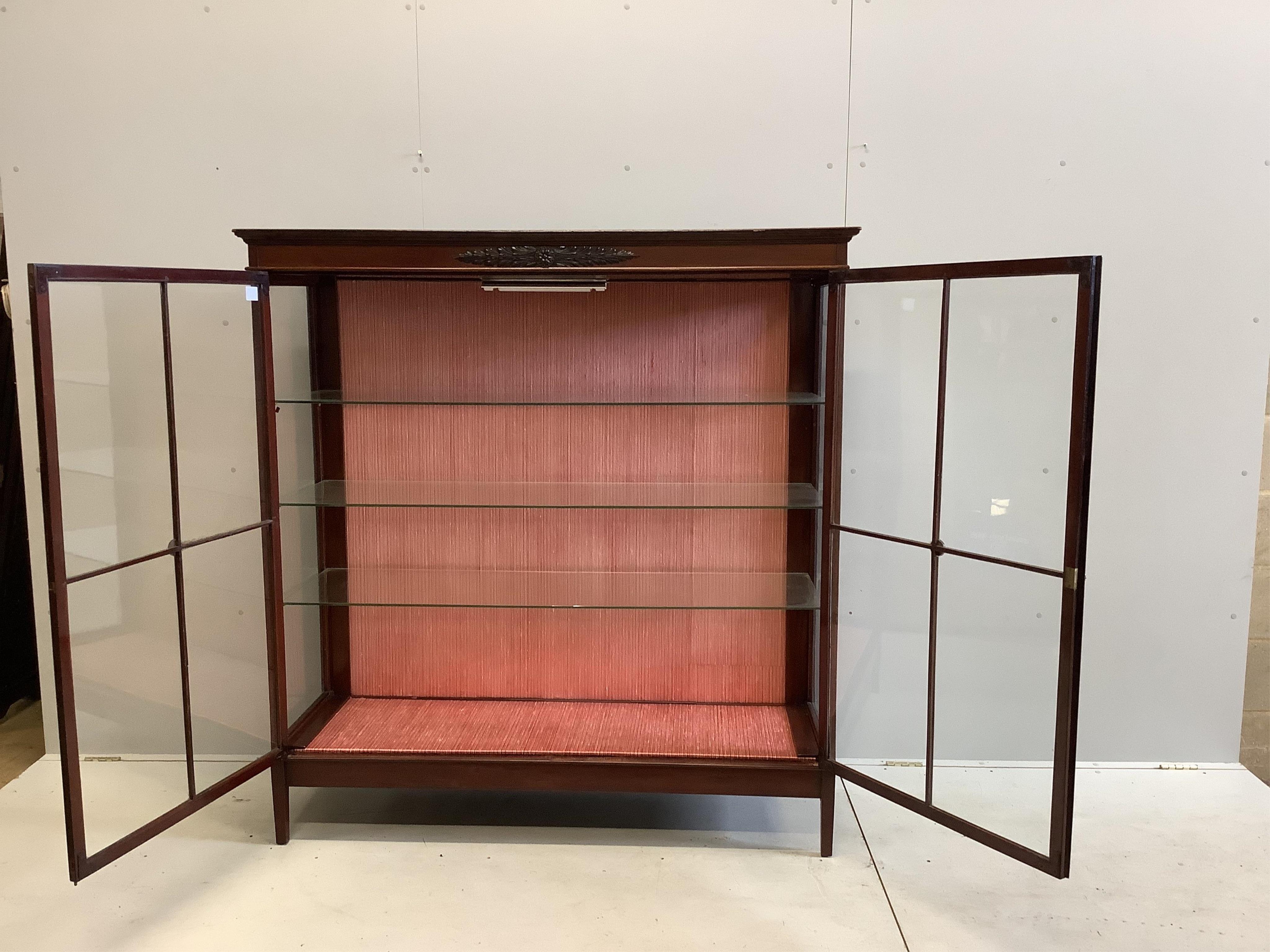 An early 20th century mahogany two door glazed display cabinet, width 148cm, depth 46cm, height 156cm. Condition - fair